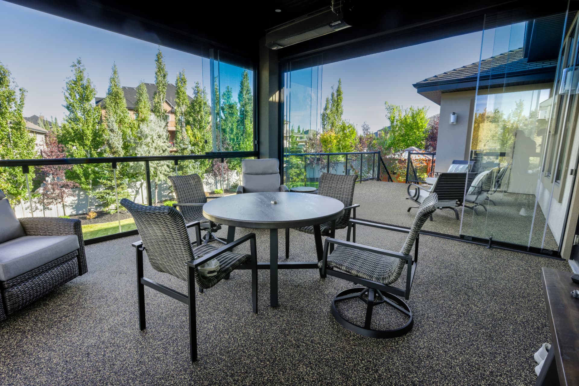 Interior of the glazed balcony with dining set and lounge chairs looking over the trees
