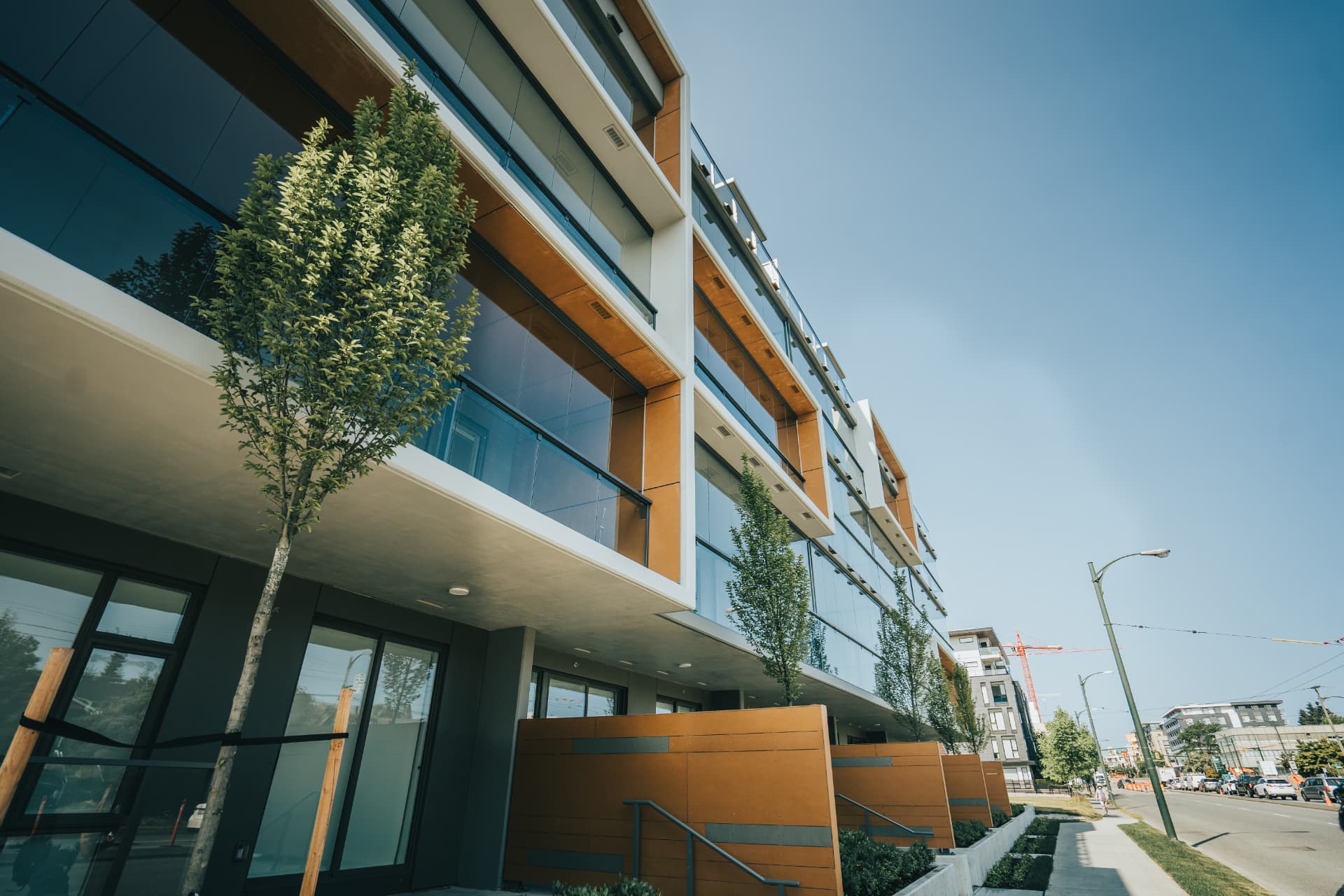 Sunny streetside view of the glazed balconies and ground-floor entries
