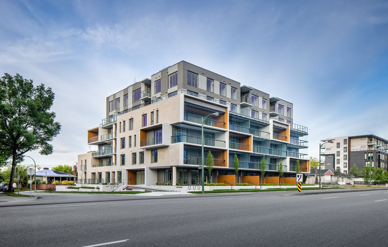 Street view of a modern multi-family building with glazed balconies on every floor
